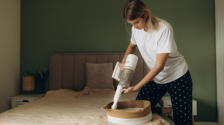Woman cleaning small dog bed with hand-held vacuum