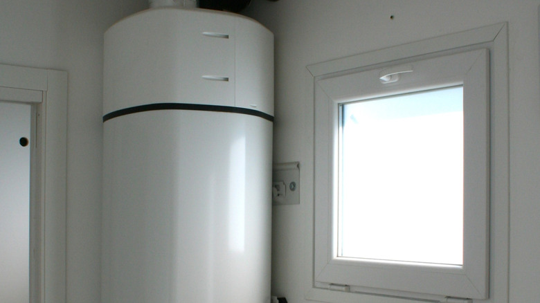A heat pump water heater installed near a basement window.