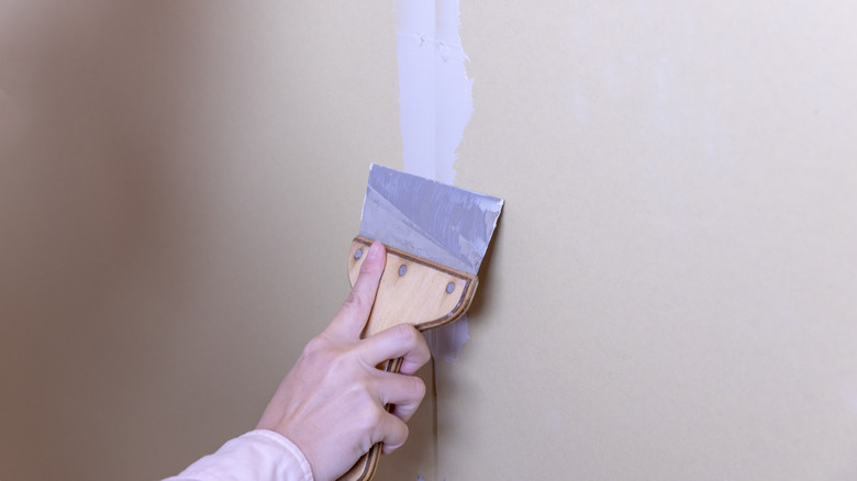 Hand applying plaster to wall imperfection