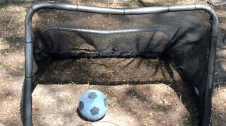 Soccer goal made out of old trampoline next to another trampoline
