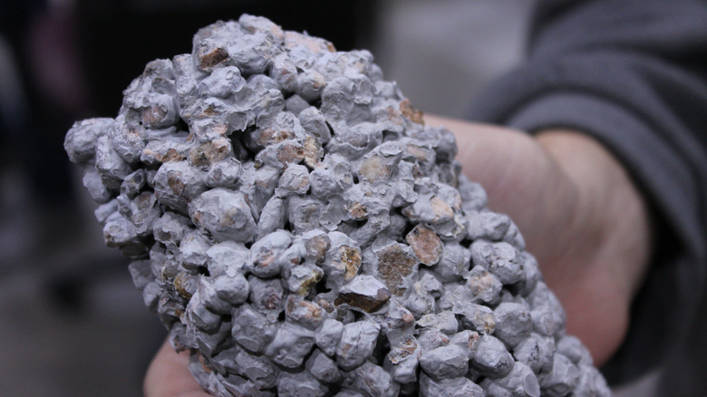 A hand holding a piece of pervious concrete to show texture