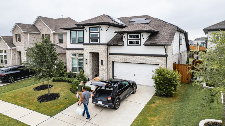 A family arriving in a plain concrete driveway