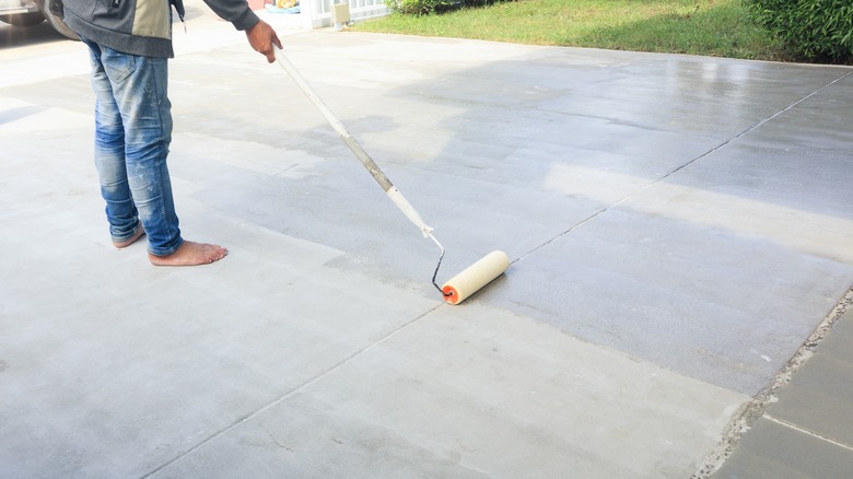 Man applying stain to concrete with a roller