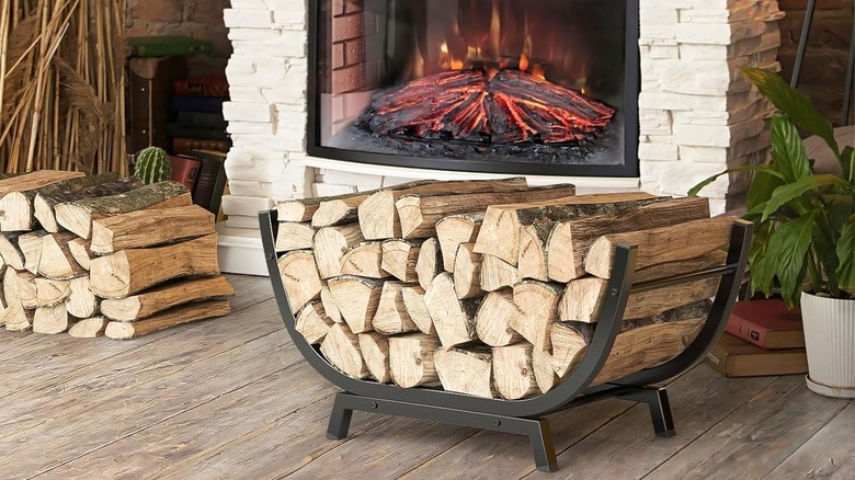 A curved metal firewood rack in front of a fireplace.