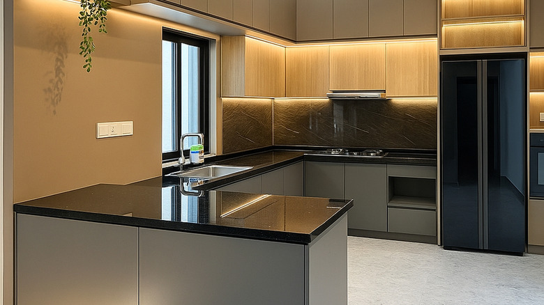 A minimalist peninsula kitchen with black countertops and light timber cabinetry.