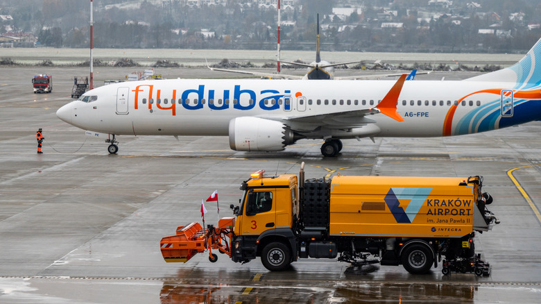 airport runway with orange icing truck in front of a plane