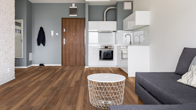 A small grand room with chestnut wood flooring and a similar wood on the door
