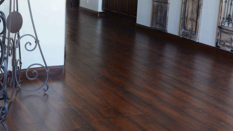 A hallway next to a staircase with a warm chocolate hardwood floor