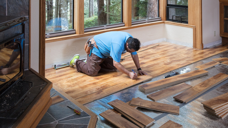 A man installing new wood flooring in a house