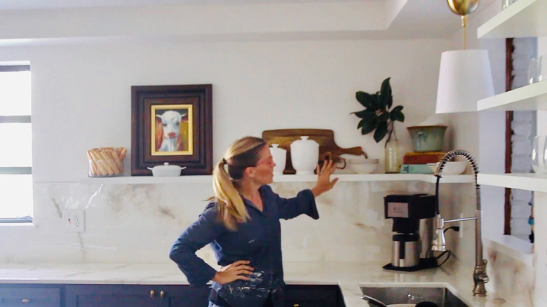 Kitchen floating shelves made from a hollow-core door hold numerous decorative and functional items.