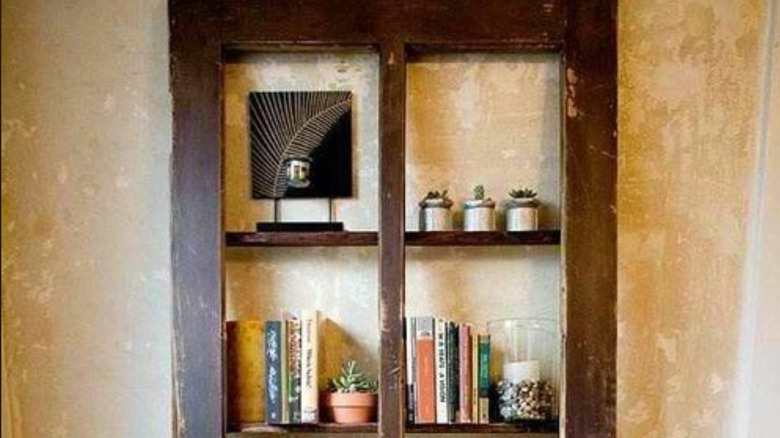 And old door with openings for window panes is used to display plants, artwork and books.