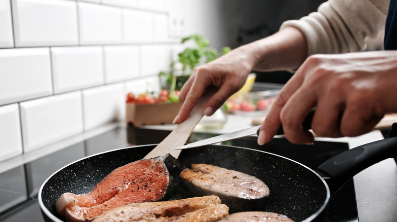 Person frying fish in a kitchen
