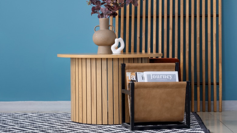 A magazine rack sitting on the floor next to a table