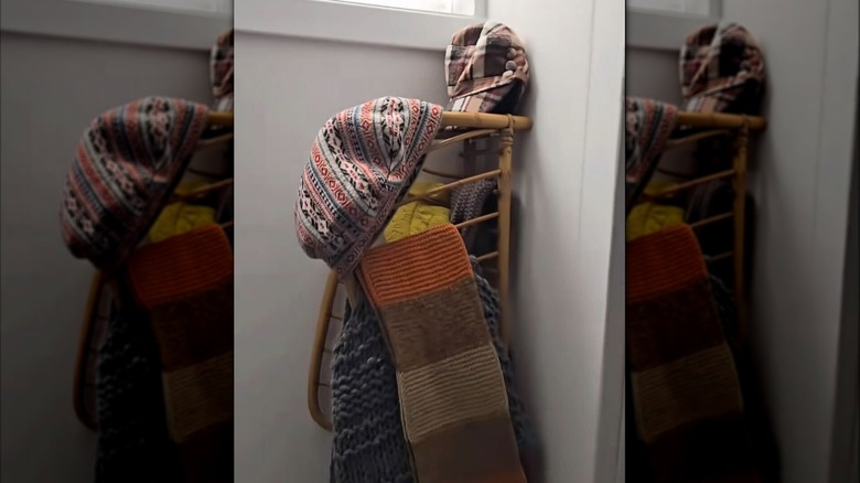 Magazine rack hung on a wall with winter accessories hanging on it