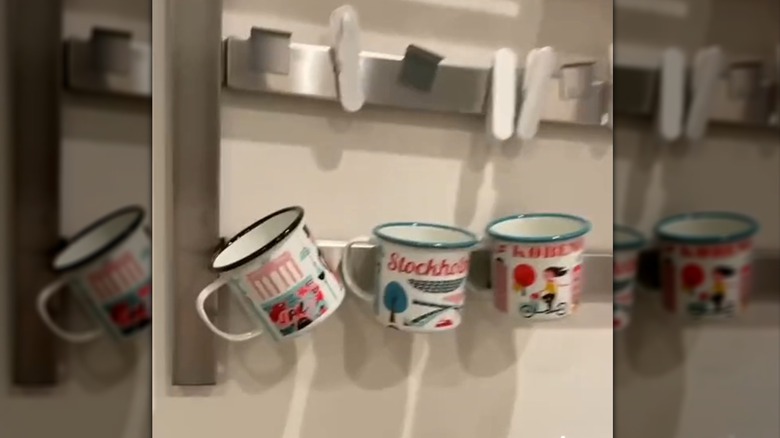 View of metal camping mugs stuck to a wall-mounted knife rack