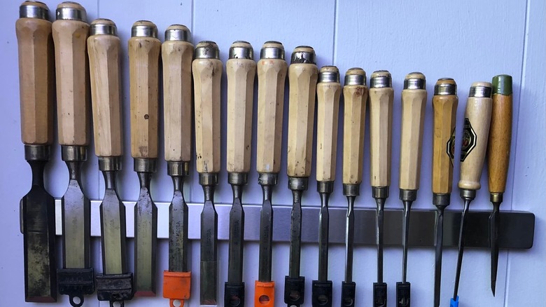 Blue-paneled wall with an IKEA magnetic knife rack covered with chisels in descending size order
