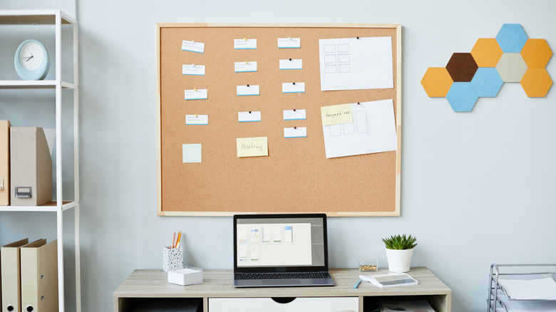 A corkboard with notes and papers in a workspace