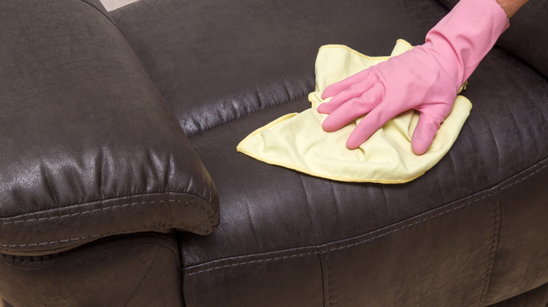 Gloved woman wiping leather upholstery