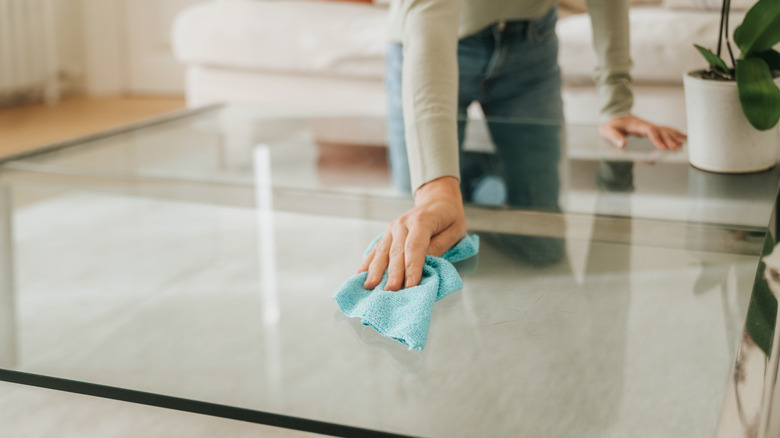 Woman cleaning glass table with microfiber cloth