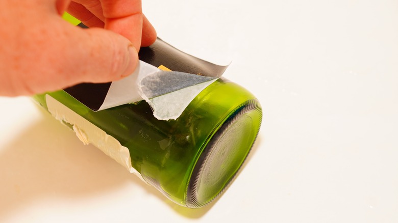 Someone removing a label off of a bottle and leaving behind residue