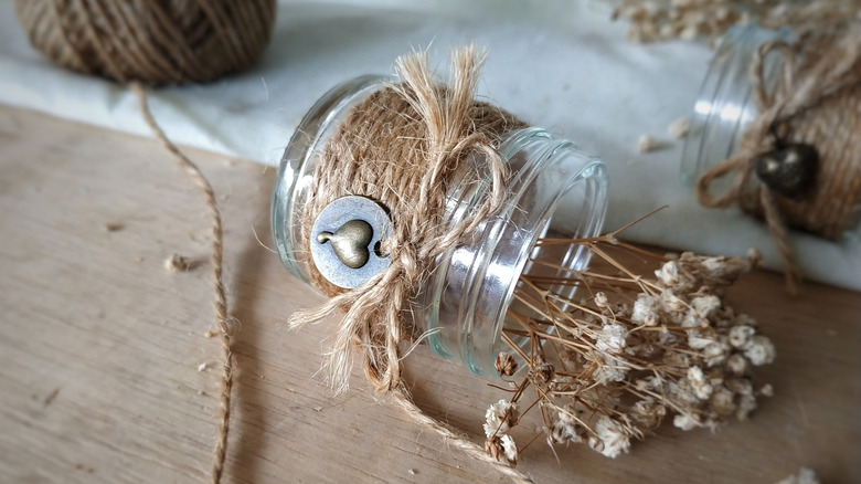 A glass jar wrapped in wine with dried flowers inside.