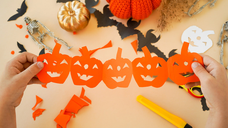 hand holding orange pumpkin garland made from craft paper