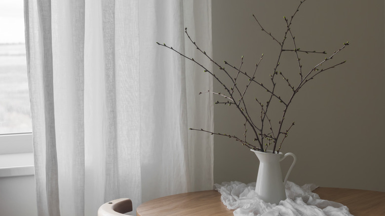 dry tree branch in a vase on a table by a window