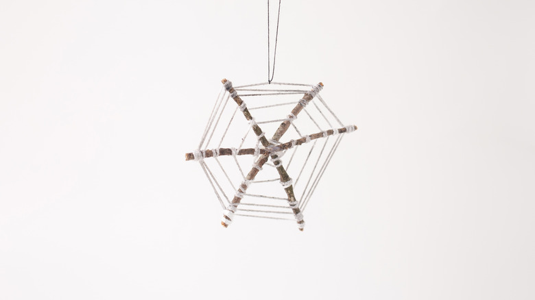 string spiderweb craft made from twigs and white yarn