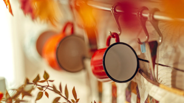 Autumnal colored mugs hanging from hooks