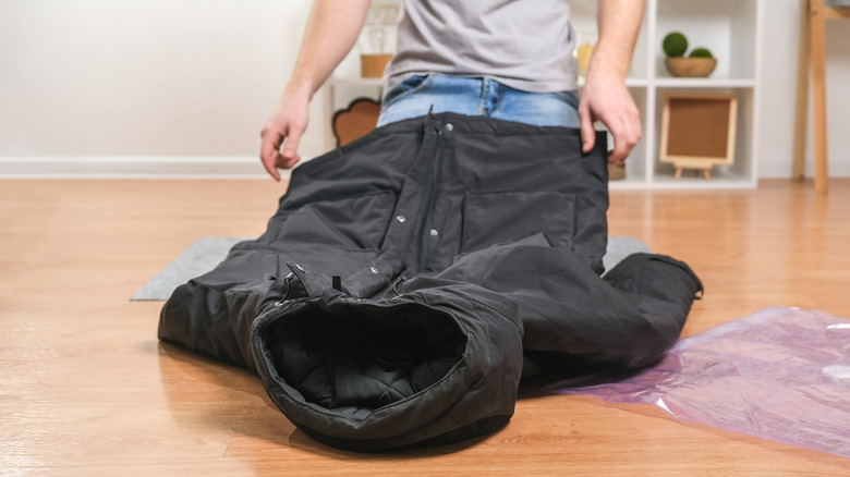 Man packing black winter coat in a vacuum bag