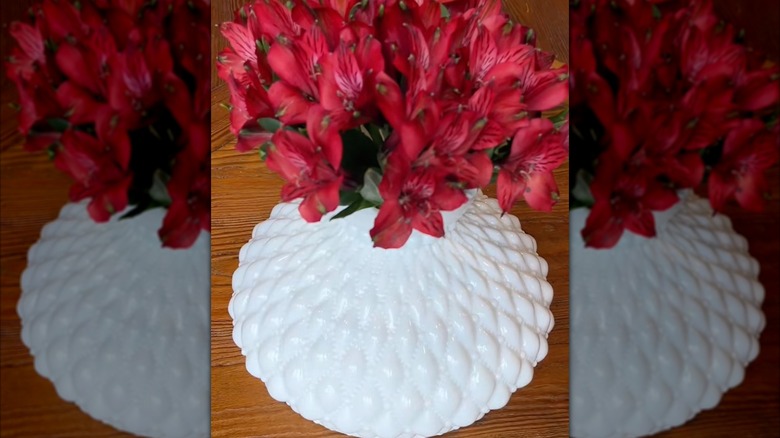 A hobnail milk-glass lampshade being used as a vase for fresh cut flowers.