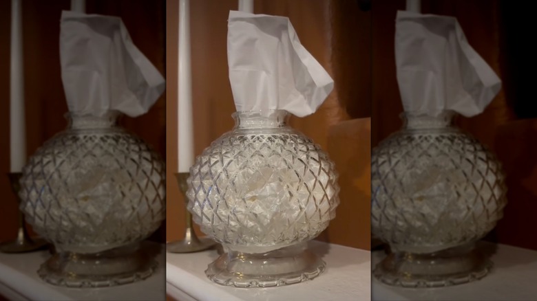 An old glass lampshade being used as a tissue holder.