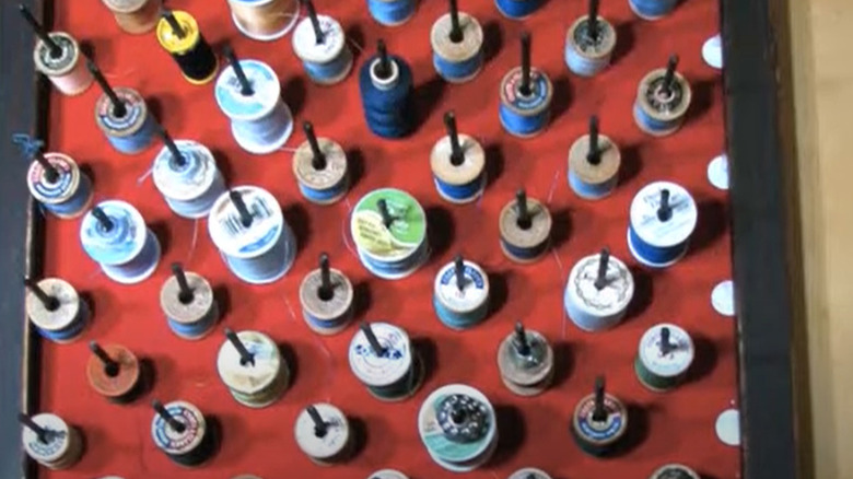 A corkboard repurposed into an organizer for spools of thread.