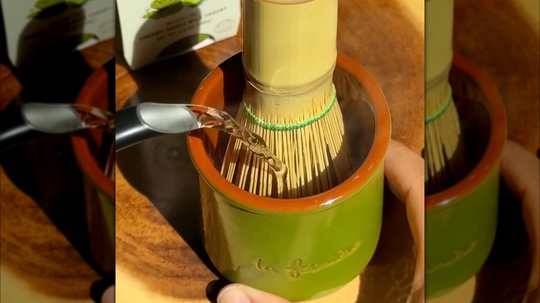 kettle pouring hot water on matcha whisk in yogurt cup