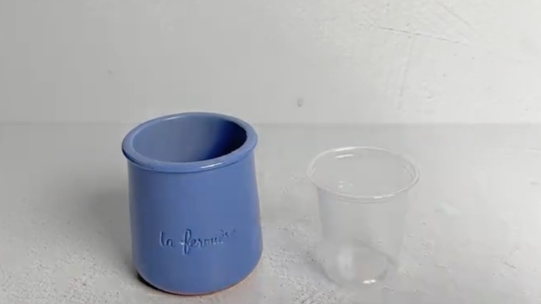 blue ceramic pot next to a small plastic cup on a table