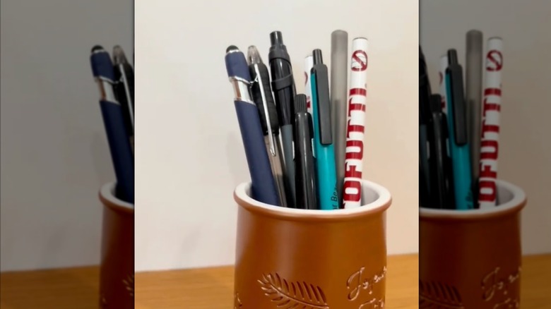 brown yogurt cup filled with pens on a table