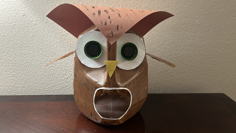 brown owl shaped milk jug bird feeder on a wood table