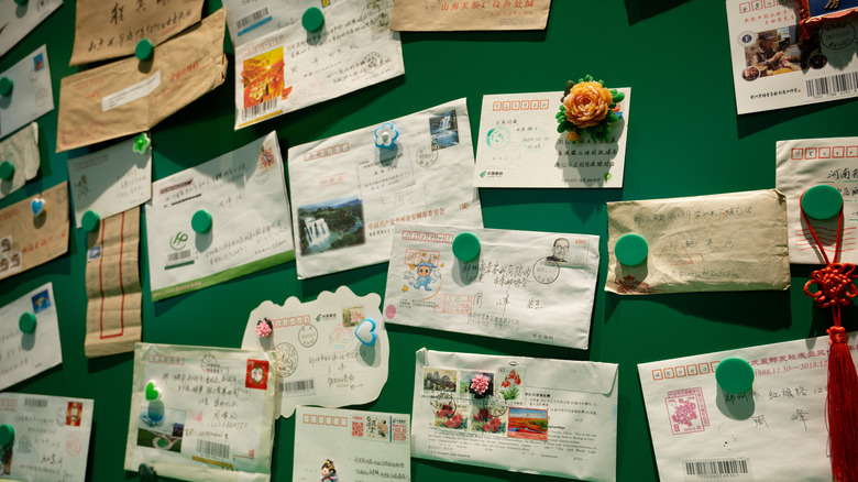 Souvenir postcards, receipts, and letters attached to a green wall with magnets