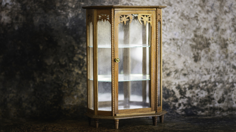 Brass curio cabinet against a mottled gray wall