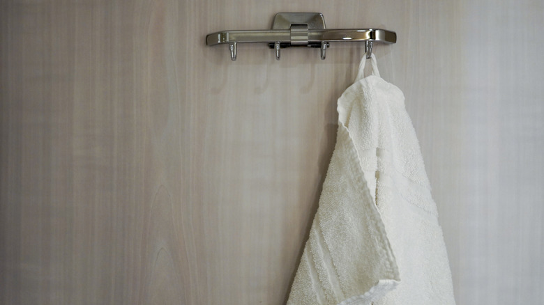 white towel hanging from rack on back of door