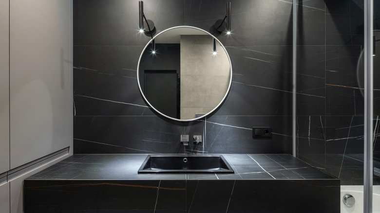 black bathroom with round mirror