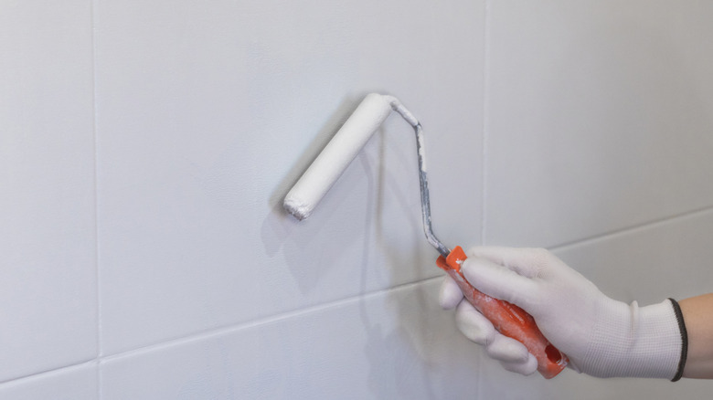person holding paint swatches against tile