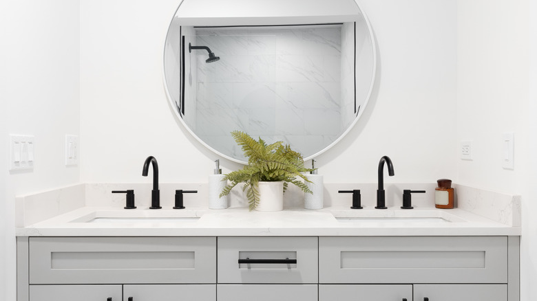 A modern bathroom with white walls and a round mirror