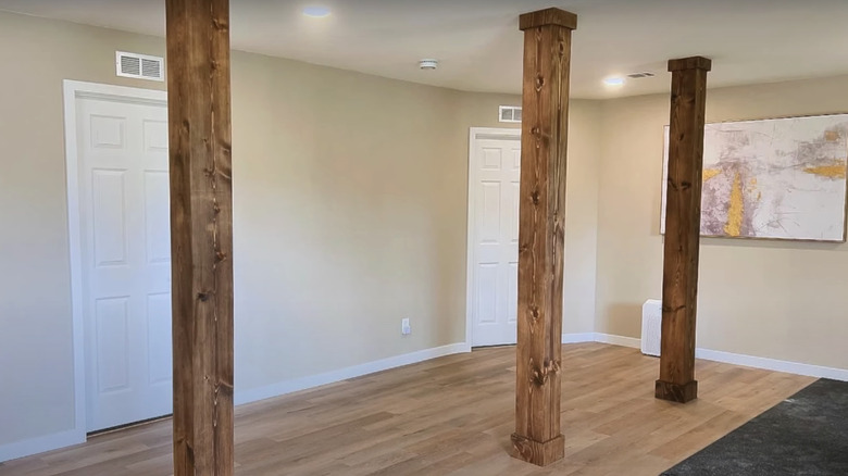 A basement with three wood columns.