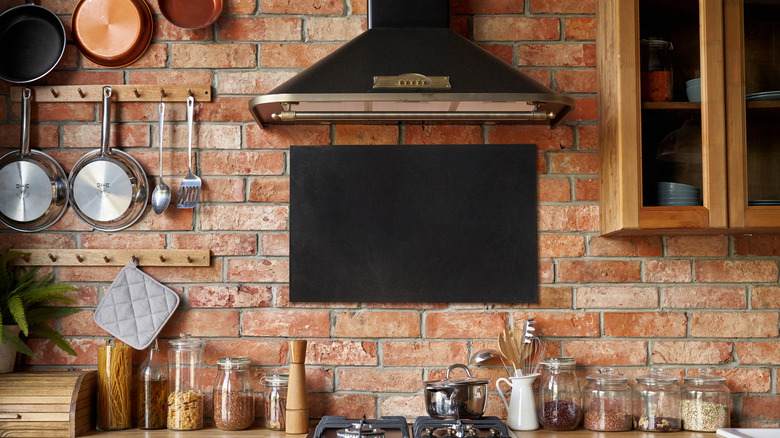 A modern kitchen with a rustic raw brick backsplash.