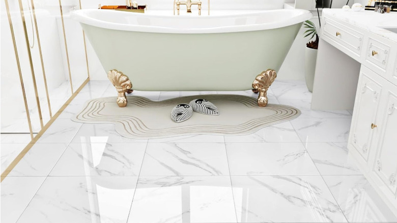 A pale green clawfoot bathtub on white, imitation marble flooring.