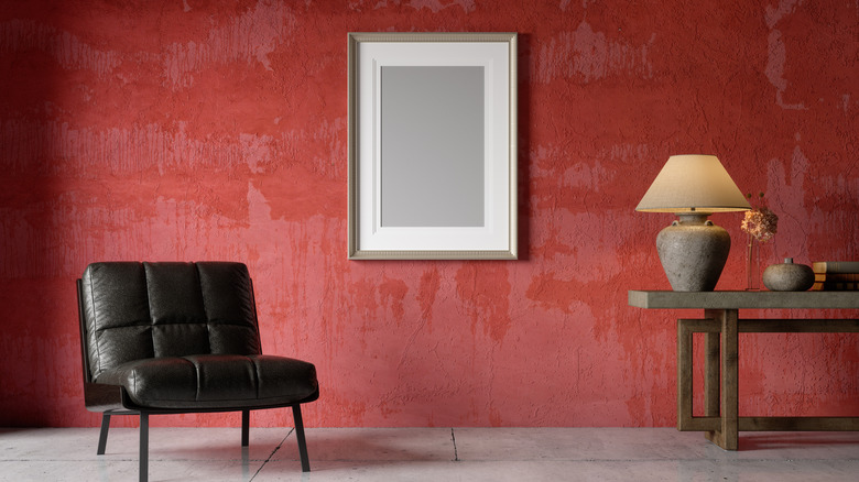 Brick red wall in a living room with a black chair and wooden table