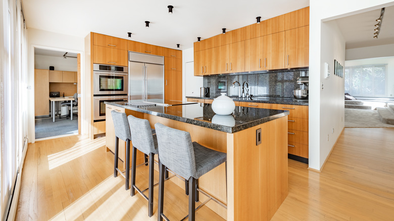 Kitchen with wood cabinets, black countertops and light bamboo floor