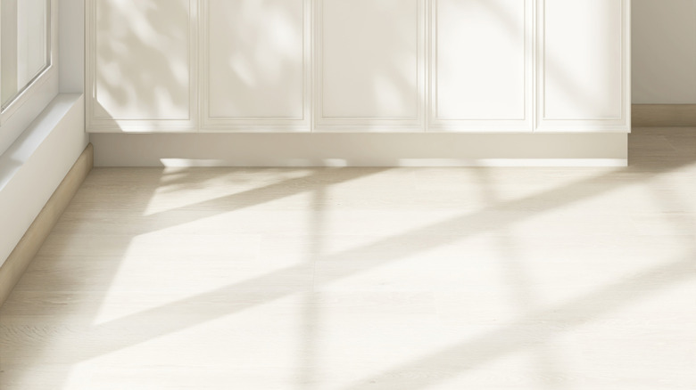 White kitchen cabinets with light laminate flooring