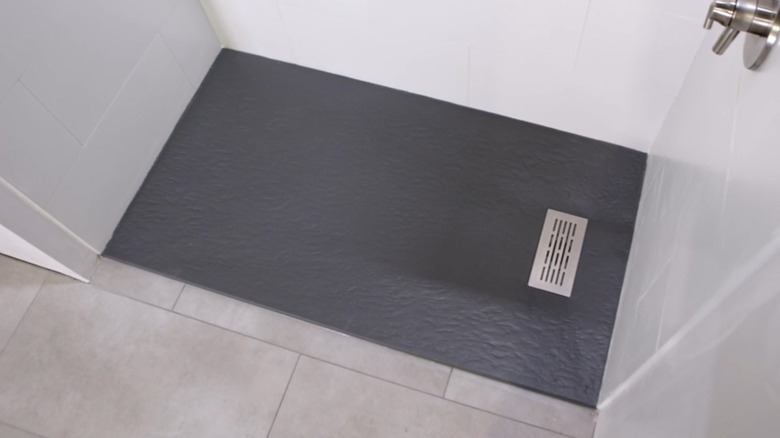 A rectangular, dark gray composite stone shower tray